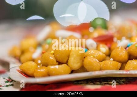 Struffoli italiani dolci fatti in casa, polpette fritte e immerse nel miele con Sprinkles. Tipico dessert napoletano delle feste natalizie. Foto Stock