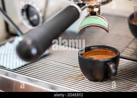 Caffè fresco in tazza di ceramica. Caffè espresso fresco che viene erogato attraverso il portafiltro senza fondo Foto Stock