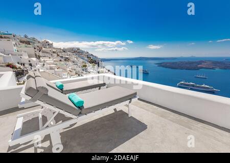 Chaise lounge a Santorini, Grecia. Paesaggio estivo di lusso, vacanza vista mare. Architettura bianca, relax sulla baia blu, navi da crociera, resort Foto Stock