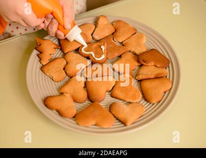 Piccolo ragazzo che decorano i biscotti fatti in casa. Ornamenti di Natale Foto Stock