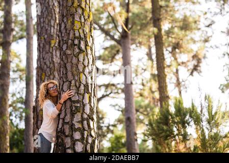 Il giorno della terra salva il pianeta rispetto del mondo con l'adulto donna che abbracciano un grande e bel pino nel foresta - la gente difende le piante - nessun concetto di deforestazione attività Foto Stock