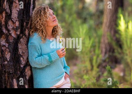 Ritratto di bella donna caucasica adulta godendo la sensazione con la natura - le persone e la foresta attività di svago - alternativa ricreazione attiva femmina con trendy maglia blu Foto Stock