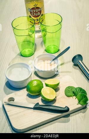 preparazione di un cocktail mojito, ingredienti su un tavolo di legno e un paio di bicchieri verdi Foto Stock