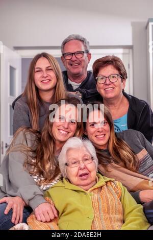 Famiglia di tre figlie, padre, madre e nonna in posa per una foto guardando la macchina fotografica Foto Stock