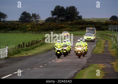 Ayrshire, Scozia, Regno Unito. La torcia olimpica di Londra 2012 viaggia attraverso l'Ayrshire del Sud, allietato dalle comunità locali e dai bambini della scuola. Il motociclo che porta la torcia e l'equipaggio di supporto arriva a Maidens, Ayrshire con scorta di polizia Foto Stock