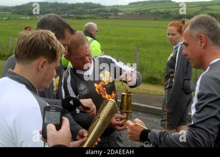 Maidens, Ayrshire, Scozia, Regno Unito. La torcia olimpica di Londra 2012 viaggia attraverso l'Ayrshire del Sud, allietato dalle comunità locali e dai bambini della scuola> illuminare la torcia da una lampada dei minatori Foto Stock