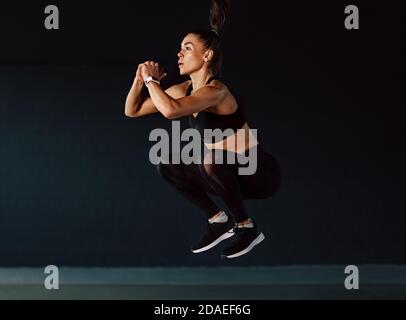 Donna sportiva che salta in palestra. Donna in forma muscolare che si esercita all'interno. Foto Stock