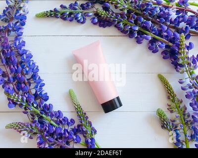 Bottiglia mock-up per marcare a caldo ed etichettare. Lupin fiori e mockup modello 3d di pink squeeze bottiglia tubo di plastica con tappo nero. Vista dall'alto. Foto Stock