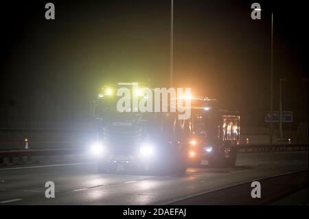 Due camion Scania che guidano vicino insieme sull'autostrada M6 durante la notte, Inghilterra, Regno Unito. Foto Stock