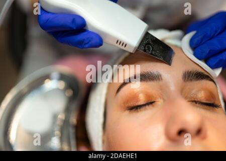 Procedura di pulizia del viso con scrubber ultrasonico Foto Stock