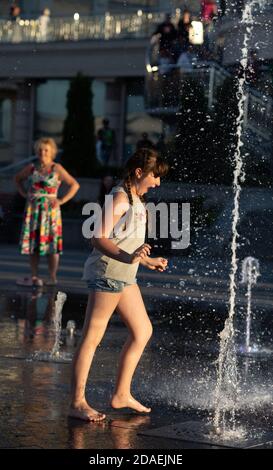 KIEV, UCRAINA - 05 giu 2018: Ragazza allegra e felice che gioca in una fontana d'acqua e godendo i flussi freddi di acqua in una giornata calda. Estate calda. Foto Stock