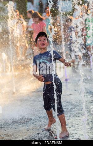 KIEV, UCRAINA - 05 giu 2018: Bambini allegri e felici che giocano in una fontana d'acqua e che si godono i freschi ruscelli d'acqua in una giornata calda. Estate calda. Foto Stock