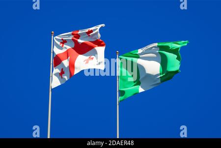 Belle bandiere nazionali di Georgia e Nigeria insieme sullo sfondo del cielo. Concetto di grafica 3D. Foto Stock