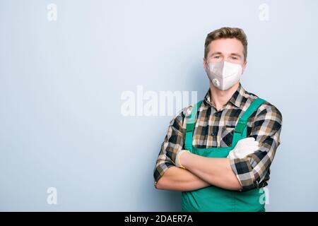 Ritratto di handyman esperto che indossa tute verdi viso respiratorio bianco maschera in piedi con le mani ripiegate isolate su sfondo grigio con spazio vuoto Foto Stock