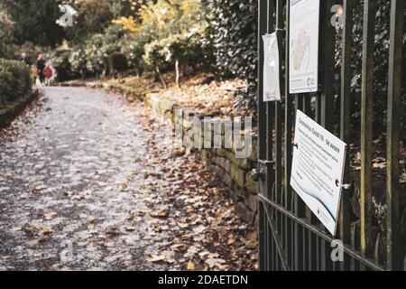 Cartelli di allontanamento sociale sulle porte del parco, con foglie autunnali sullo sfondo. Tiro a Grosvenor Park, Chester. Foto Stock