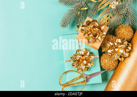 Regali di Natale che avvolgono una composizione piatta con scatole, nastri dorati e rami di abete su sfondo blu. Foto Stock