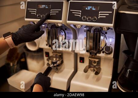 Barista esperto che utilizza macinacaffè moderno al lavoro Foto Stock