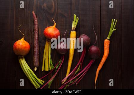 Vista dall'alto delle barbabietole dorate e rosse e delle carote multicolore su una superficie di legno con spazio per la copia Foto Stock