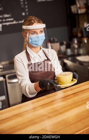 Tazza di caffè sul piatto in mani di grazioso cameriera Foto Stock