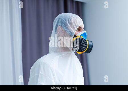 Uomo in abbigliamento protettivo e maschera a gas su fondo bianco Foto Stock