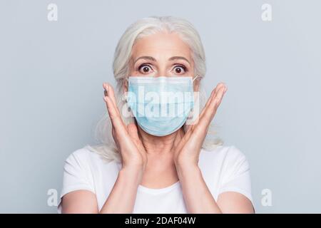Ritratto fotografico di vecchia signora scioccata che indossa una maschera blu isolato su sfondo bianco Foto Stock