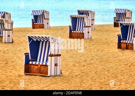 Cestelli vuoti in corda bianca con coperture a strisce blu e bianche su una spiaggia di sabbia con il mare sullo sfondo Foto Stock