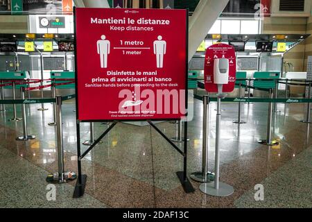 Il cartello all'aeroporto di Olbia in Sardegna ricorda ai passeggeri di mantenere la distanza sociale e disinfettare le mani durante la crisi del coronavirus in Italia. Foto Stock