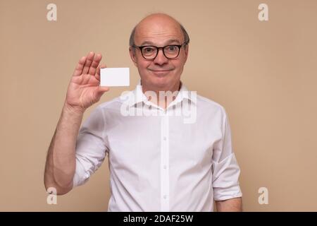 Uomo caucasico anziano che tiene in bianco la scheda di visita Foto Stock