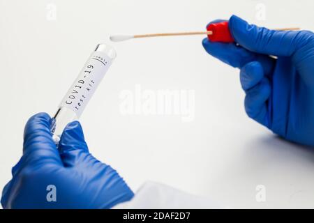 COVID-19 Coronavirus Global Pandemic, guanti a mani libere per provette con tampone, kit per la raccolta dei campioni per pazienti PCR a domicilio, provetta Vacutainer sterile per campioni Foto Stock