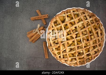 Mele fresche, bastoncini di cannella e classica torta americana vista dall'alto. Sfondo grigio con spazio per la copia. Foto Stock