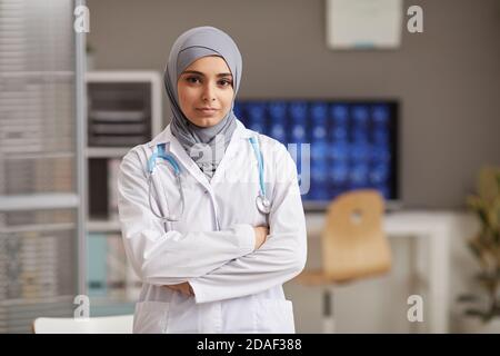 Ritratto di medico musulmano in mano bianco in piedi con lei braccia incrociate all'ospedale guardando la macchina fotografica Foto Stock
