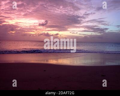 Suggestivo paesaggio della spiaggia di Antigua al tramonto, tramonto rosa e giallo sul mare Foto Stock