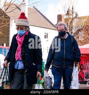 Londra UK, novembre 12 2020, UNA coppia uomo anziana che indossa coperture protettive del viso che trasportano lo shopping durante il Lockdown di Coronavirus Foto Stock