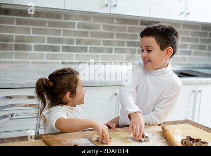 Fratello e sua sorella sorridono l'uno all'altro mentre preparano i biscotti di Natale. Foto Stock