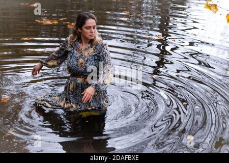 Donna che indossa un abito, all'interno dell'acqua in un giorno d'autunno Foto Stock