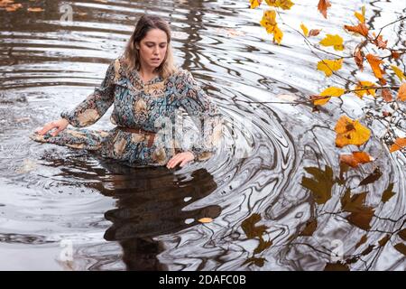 Donna che indossa un abito, all'interno dell'acqua in un giorno d'autunno Foto Stock