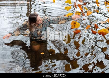 Donna che indossa un abito, all'interno dell'acqua in un giorno d'autunno Foto Stock