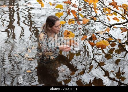 Donna che indossa un abito, all'interno dell'acqua in un giorno d'autunno Foto Stock