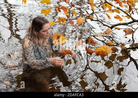 Donna che indossa un abito, all'interno dell'acqua in un giorno d'autunno Foto Stock