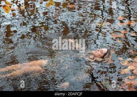 Donna che indossa un abito, all'interno dell'acqua in un giorno d'autunno Foto Stock