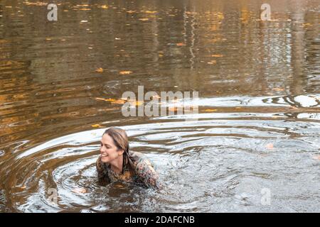 Donna che indossa un abito, all'interno dell'acqua in un giorno d'autunno Foto Stock