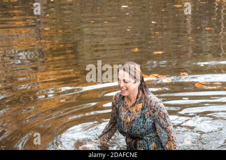Donna che indossa un abito, all'interno dell'acqua in un giorno d'autunno Foto Stock