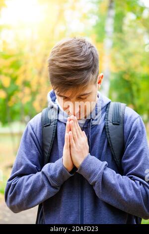 Il giovane uomo sta pregando solo nella foresta d'autunno Foto Stock