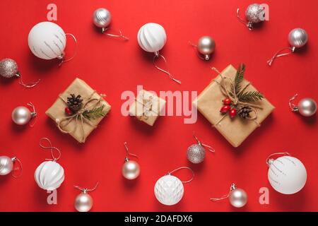 Composizione di Natale. Cornice fatta di regali di natale e palline bianche, isolato su sfondo rosso. Disposizione piatta, vista dall'alto Foto Stock
