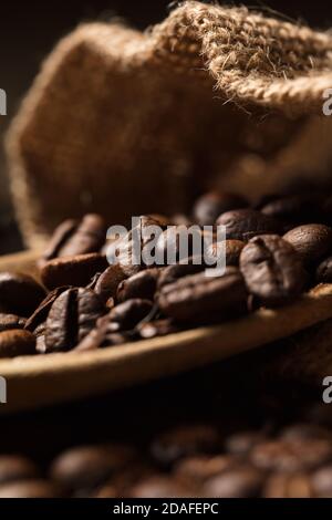 cucchiaio di legno, con fagioli e sacco di caffè naturale, su tela di rafia e fondo marrone Foto Stock
