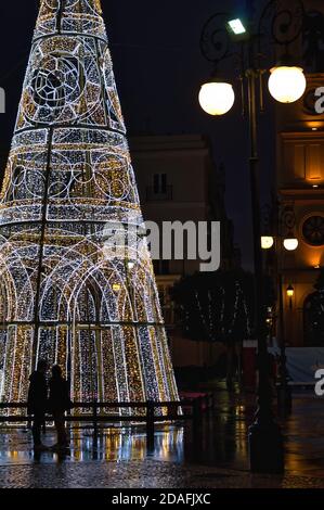 Una coppia che ammira un grande albero di Natale in una piazza a Cadice, Spagna. Foto Stock