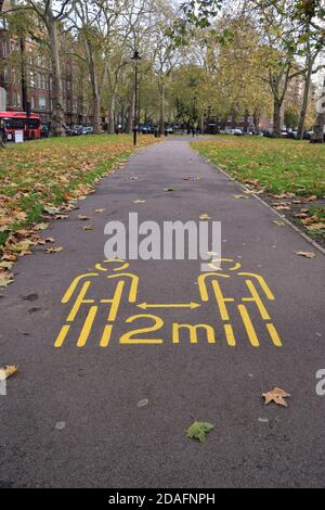 Segno di allontanamento sociale in un vuoto Goldington Crescent Gardens a Camden durante il secondo blocco nazionale in Inghilterra. Foto Stock