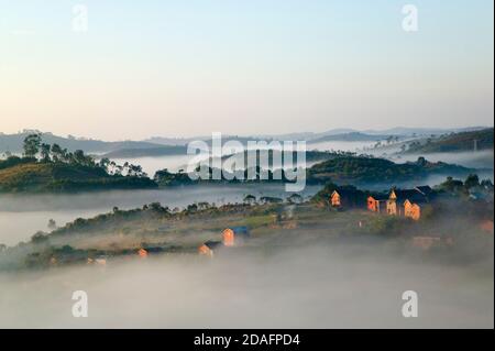 Paesaggio di case di villaggio con foresta pluviale tropicale in montagna in mattina nebbia, vicino Perinet, Madagascar Foto Stock