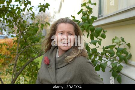 donna con occhi blu intenso e camice grigio all'aperto in un'area urbana e verde Foto Stock