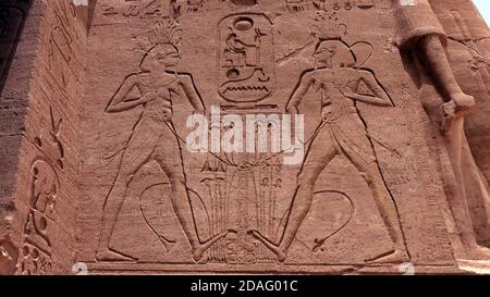 Antiche incisioni egiziane di persone e geroglifici all'esterno muro di un antico tempio Foto Stock